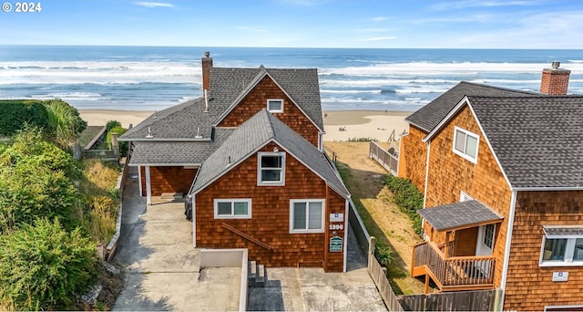 view of front of house featuring a water view, a chimney, and a shingled roof