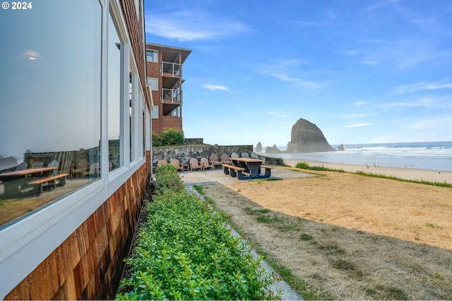 view of yard with a beach view, a water view, and a patio