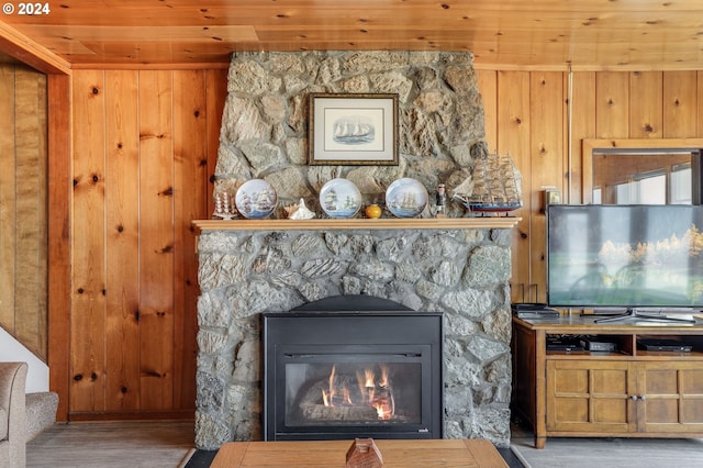 room details with a stone fireplace, wood ceiling, wood finished floors, and wooden walls