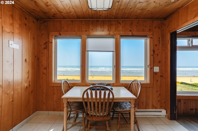 tiled dining area with a baseboard heating unit, wooden walls, and a water view