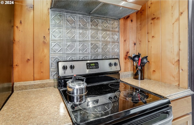 details featuring stainless steel electric range oven, wooden walls, under cabinet range hood, and light countertops