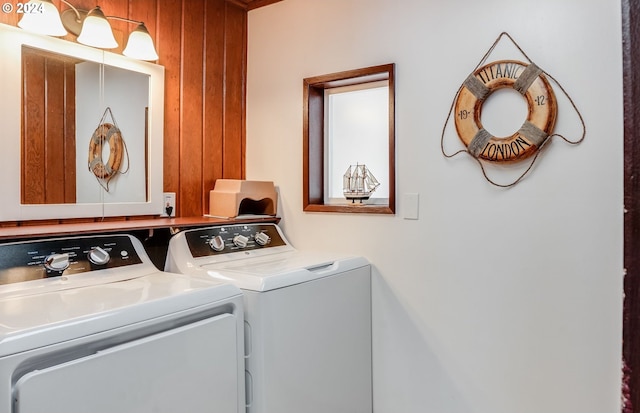 washroom featuring washing machine and dryer and wood walls