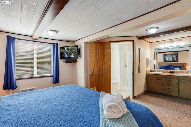 carpeted bedroom featuring ensuite bath, beamed ceiling, ornamental molding, and sink