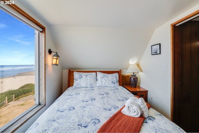 bedroom with a water view, a beach view, vaulted ceiling, and multiple windows