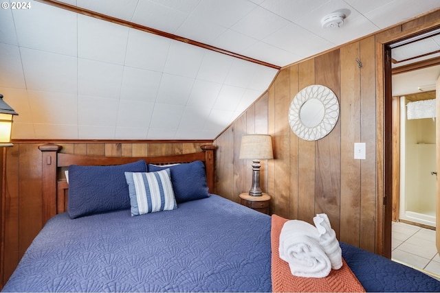 bedroom featuring vaulted ceiling and wood walls