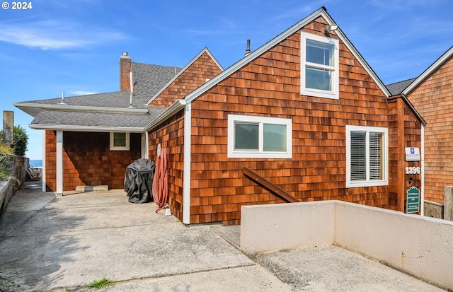 back of property featuring roof with shingles and a chimney