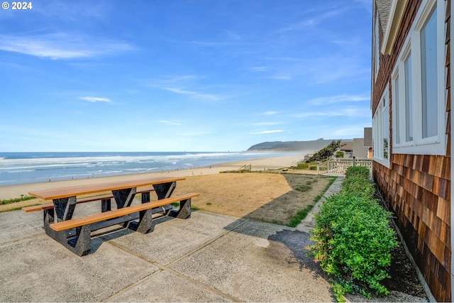 view of community with a water view, a view of the beach, and a patio area