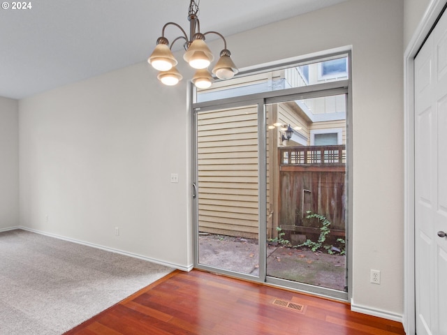 unfurnished dining area with hardwood / wood-style flooring and a chandelier