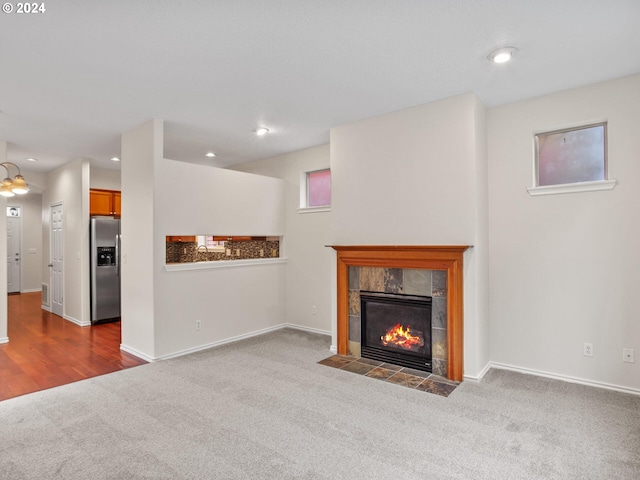 unfurnished living room featuring a tiled fireplace and carpet