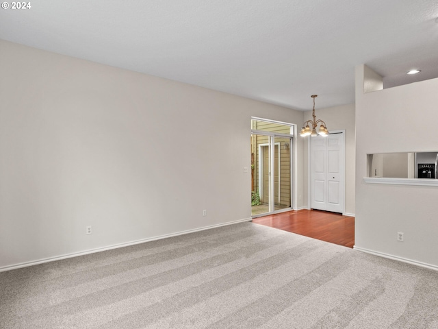 carpeted spare room featuring an inviting chandelier