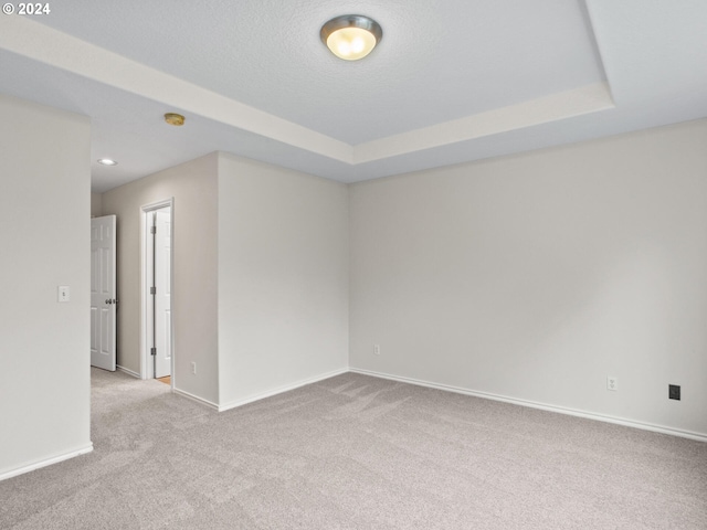 carpeted spare room with a tray ceiling