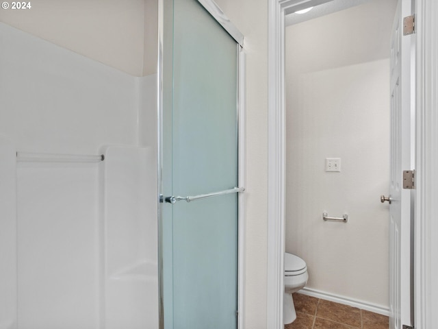 bathroom with toilet, tile patterned flooring, and a shower with shower door