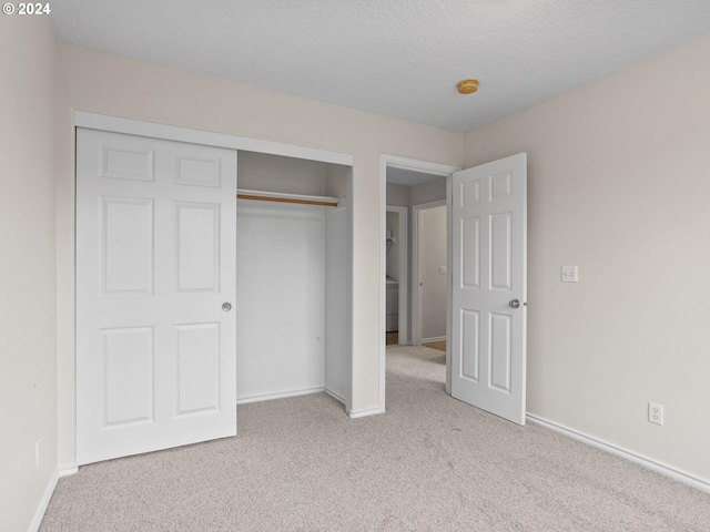 unfurnished bedroom featuring light colored carpet, a textured ceiling, and a closet