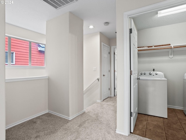 laundry area with separate washer and dryer, a textured ceiling, and carpet