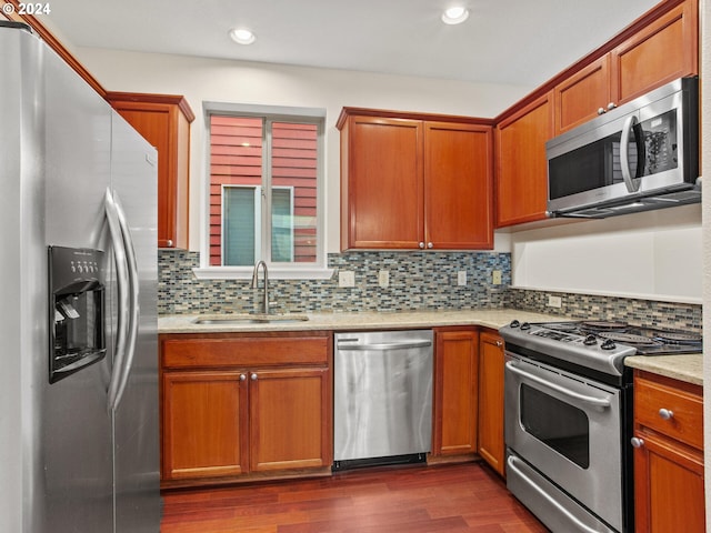 15771 SW Harvester Ln, Sherwood, OR 97140 - kitchen with stainless steel appliances, a sink, dark wood-style flooring, backsplash, and brown cabinetry