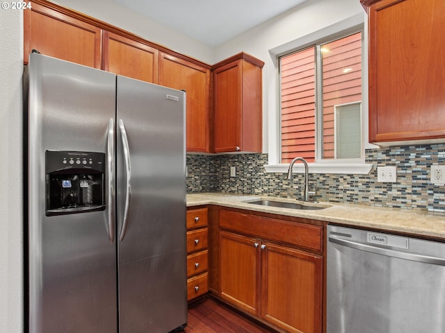 kitchen featuring stainless steel appliances, sink, light stone counters, dark hardwood / wood-style floors, and backsplash