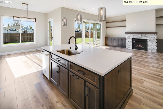 kitchen with an island with sink, light hardwood / wood-style floors, a healthy amount of sunlight, and pendant lighting