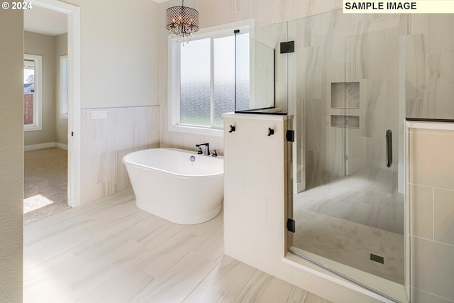 bathroom with an inviting chandelier, tile flooring, shower with separate bathtub, and tile walls