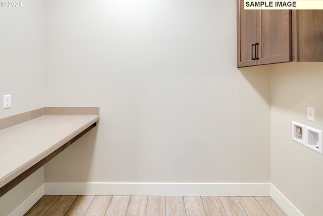 laundry room with hookup for a washing machine, light hardwood / wood-style floors, and cabinets