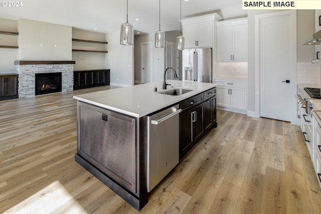 kitchen with backsplash, stainless steel appliances, sink, and light hardwood / wood-style flooring