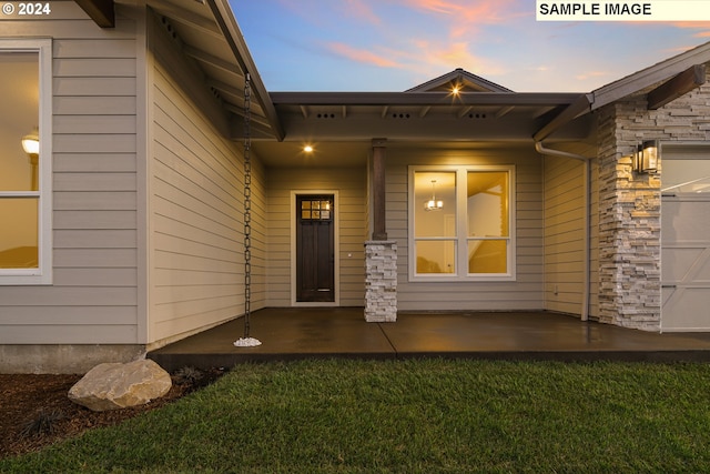 exterior entry at dusk featuring a lawn