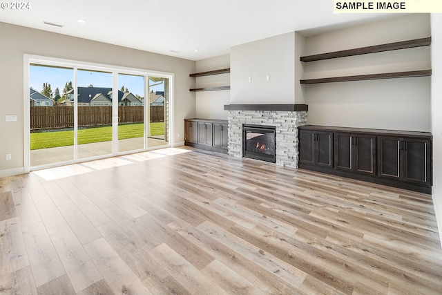 unfurnished living room featuring a stone fireplace and light hardwood / wood-style flooring