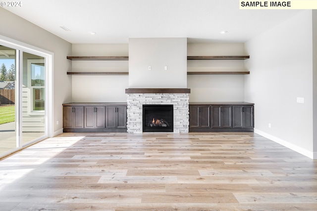 unfurnished living room with light hardwood / wood-style flooring and a stone fireplace