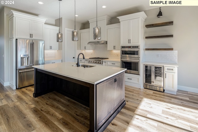 kitchen with appliances with stainless steel finishes, backsplash, a center island with sink, wine cooler, and decorative light fixtures