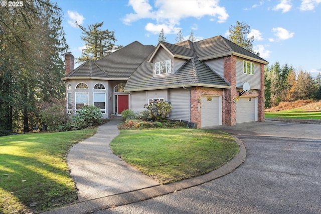 view of front facade with aphalt driveway, brick siding, an attached garage, and a front lawn