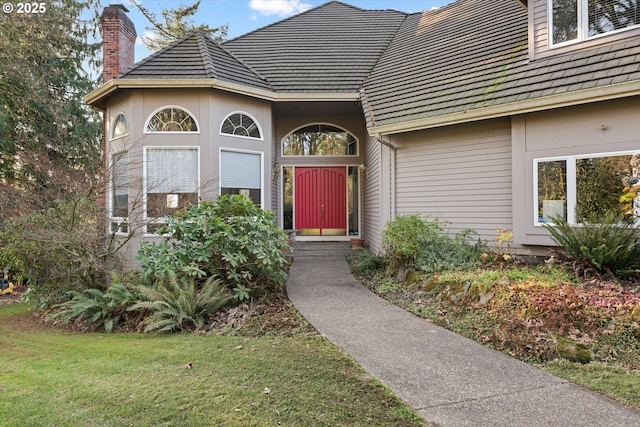 view of exterior entry featuring a yard and a chimney