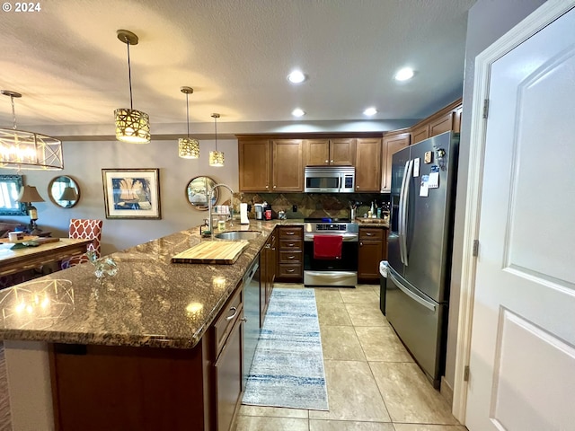 kitchen with kitchen peninsula, sink, stainless steel appliances, and decorative light fixtures