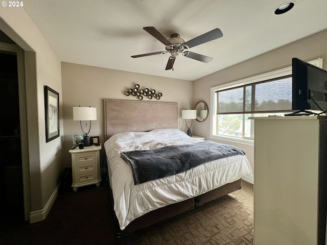 bedroom featuring ceiling fan and dark carpet