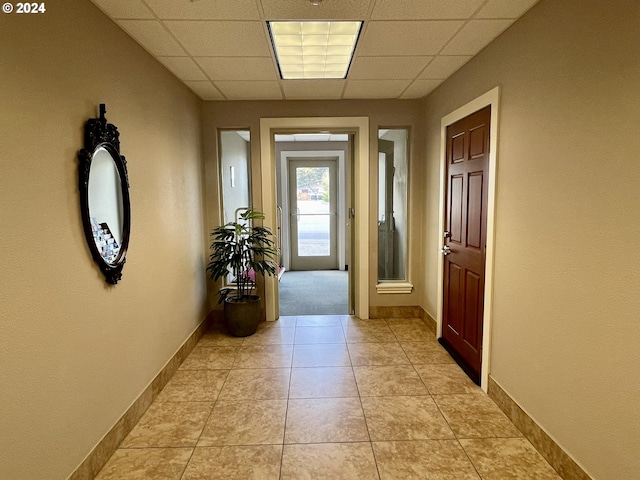 hall with light tile patterned floors and a drop ceiling