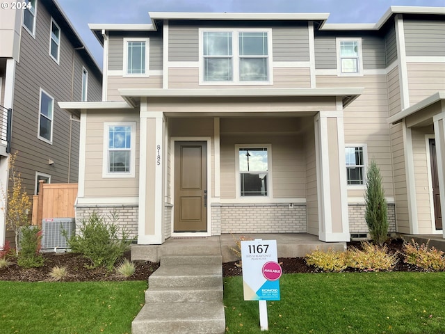 view of exterior entry with a yard and central AC