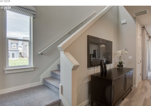 stairs featuring wood-type flooring and a chandelier