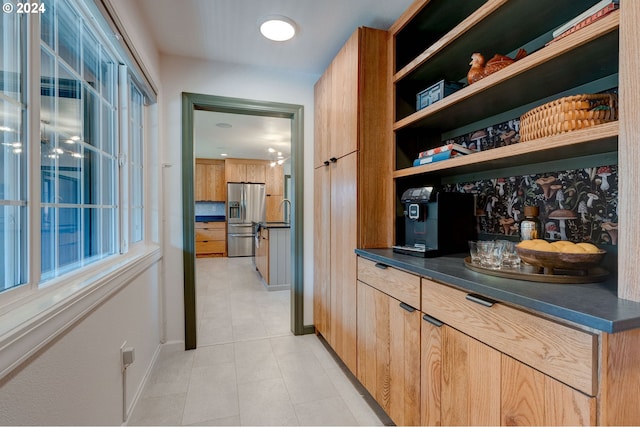 bar featuring stainless steel fridge with ice dispenser, light tile patterned floors, and sink