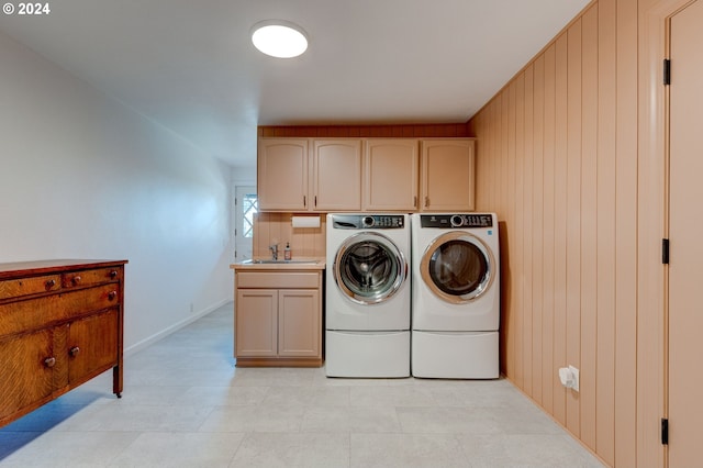 washroom with washer and dryer, cabinets, sink, and wooden walls