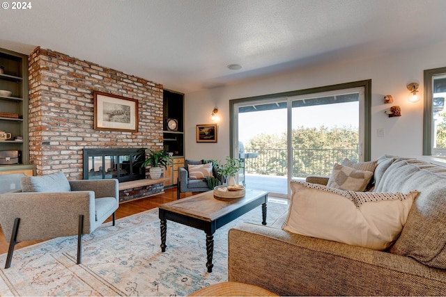 living room with a fireplace, built in shelves, light wood-type flooring, and plenty of natural light