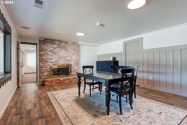 dining room with dark hardwood / wood-style flooring, a brick fireplace, and crown molding