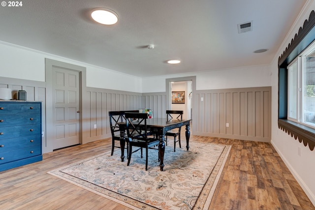 dining space featuring a textured ceiling, hardwood / wood-style flooring, and ornamental molding