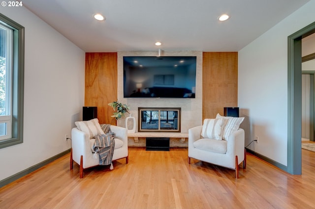 sitting room featuring wood-type flooring and a large fireplace