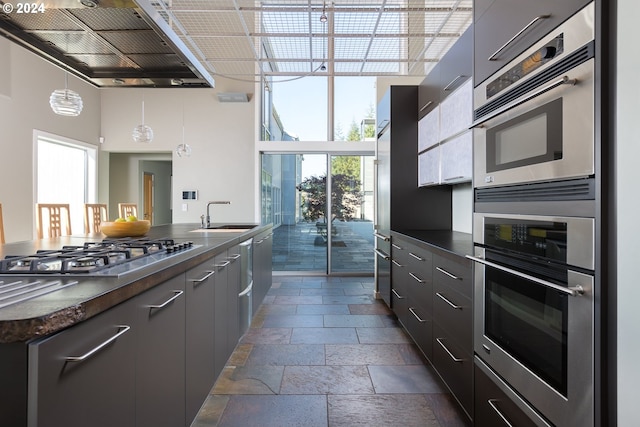 kitchen with sink, appliances with stainless steel finishes, decorative light fixtures, and plenty of natural light