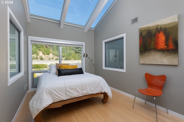 bedroom featuring light hardwood / wood-style floors and lofted ceiling with skylight