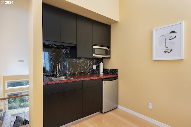 kitchen with sink, decorative backsplash, light hardwood / wood-style flooring, and stainless steel appliances