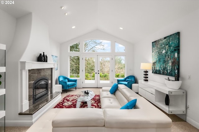 living room featuring a high end fireplace, french doors, vaulted ceiling, and a healthy amount of sunlight