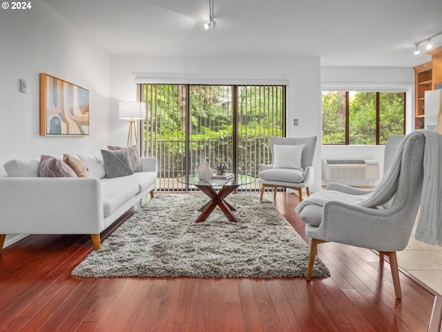 living room with track lighting, hardwood / wood-style floors, and a wall mounted air conditioner