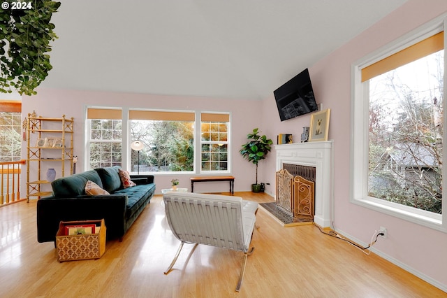 living room with lofted ceiling, light wood-type flooring, and a wealth of natural light