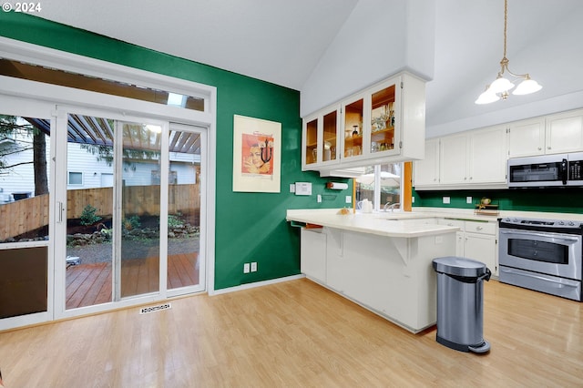 kitchen with white cabinetry, stainless steel appliances, kitchen peninsula, pendant lighting, and a kitchen bar