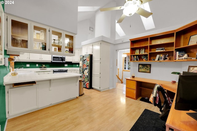 kitchen with tile countertops, white cabinetry, fridge, and stainless steel electric range oven