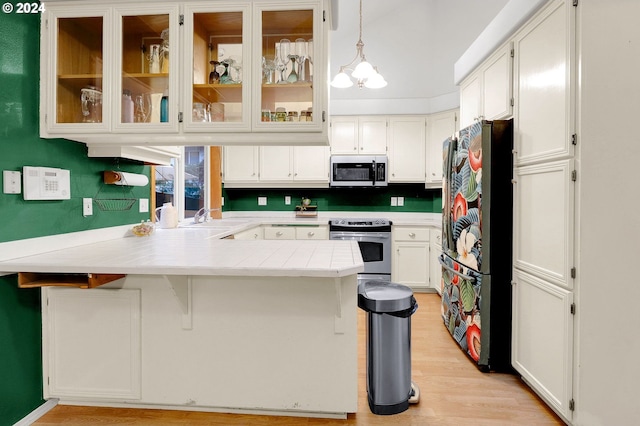 kitchen featuring pendant lighting, white cabinets, kitchen peninsula, and appliances with stainless steel finishes